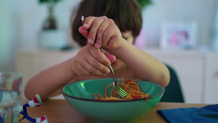 Closeup small boy eating pasta noodles, twisting and turning spaghetti meal with fork © Marco