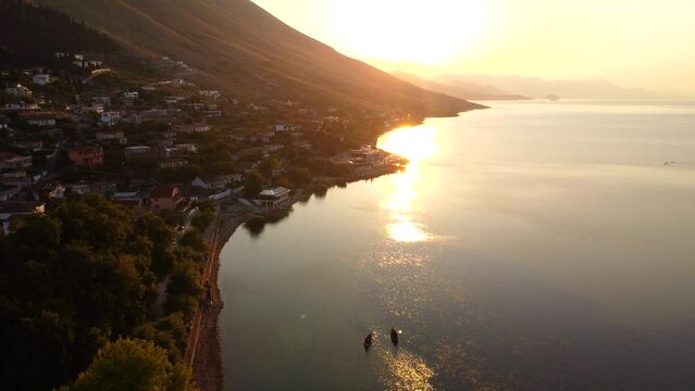 Aerial drone view of Shiroka lake at sunset with the sun on the mountain near Shkoder. Albania