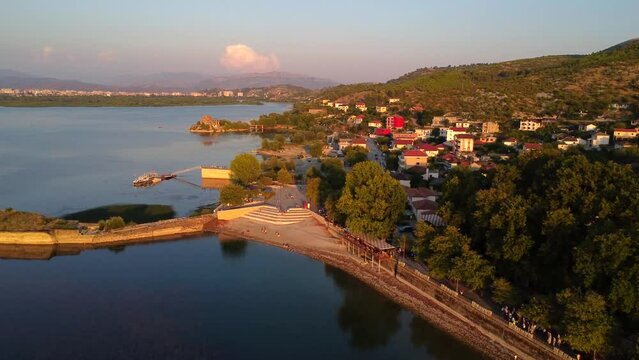 Aerial drone view of Shiroka lake at sunset with the sun near Shkoder. Albania. Forward panning plane