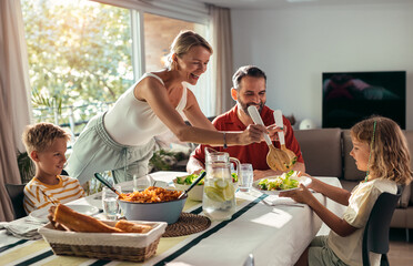 Beautiful kind family talking while eating together in the kitchen at home