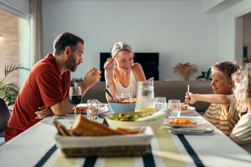 Beautiful kind family talking while eating together in the kitchen at home