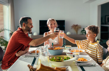Fototapeta na wymiar Beautiful kind family toasting while eating together in the kitchen at home