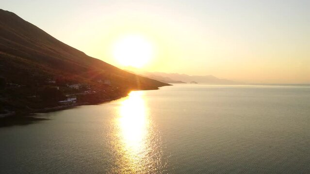 Aerial drone view of Shiroka Lake at sunset near Shkoder. Albania. Panning shot towards the sun on the mountain