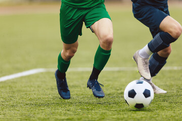 Adult football competition. Soccer football player dribbling a ball and kick a ball during match in the stadium. Footballers in action on the tournament game. - obrazy, fototapety, plakaty