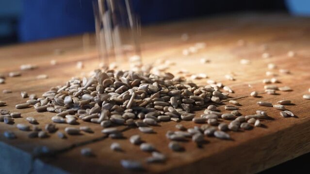 Peeled sunflower seeds drop from above on wooden board. Close-up.