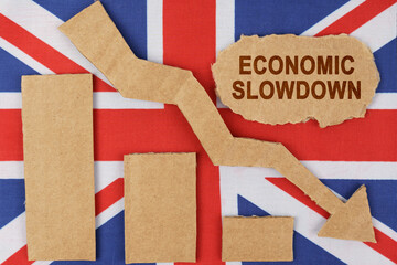 On the flag of Great Britain lie a chart, a down arrow and a sign that says - economic slowdown