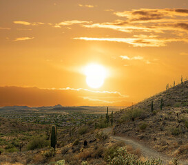 A desert trail on a mountain leading to a sunset over a valley in Phoenix, Arizona.