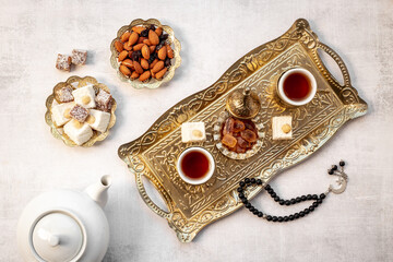 Ramadan party table with tea on bronze tray and Muslim rosary with a crescent moon