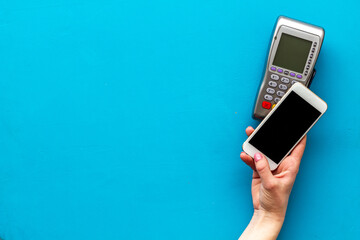 Payment by mobile phone pay. Female hand with mobile phone near POS payment terminal