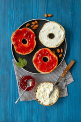 Baked bread bagels with with berry jam and cheese cream. Healthy breakfast background