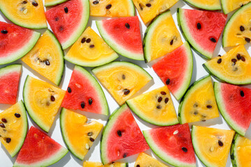 Fototapeta na wymiar fresh sliced yellow and red pieces of watermelon like background, flat lay with hard shadow on white background, creative decoration of summer concept