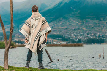 Model wearing a poncho handmade with sheep cloth by the indigenous Kichwa artisan communities of the area, posing at the San Pablo lake in Otavalo, Ecuador.