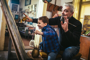 Father and son working and painting together in art studio
