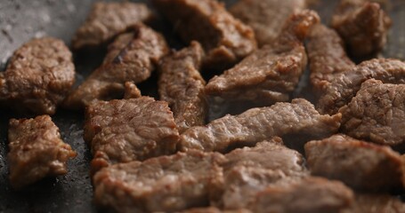 Sliced pieces of meat are fried in a frying pan. Roasting beef in a pan. Cooking in the kitchen. Food preparation. Close-up shot.