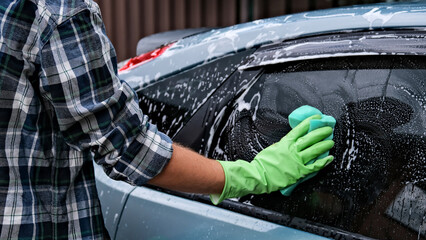 a man washes a car with foam. washing the car with a special tool for washing the car. foam sponge