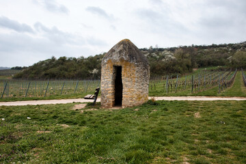 Stone building in front of a vineyard next to a walking path on a cloudy spring day in rural...