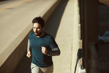 Fototapeta na wymiar Young man sprinting and exercising on a bridge in the US