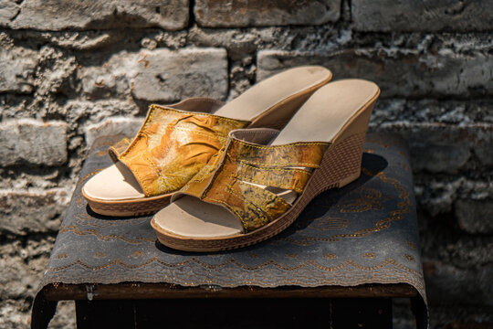 Making ecoprint crafts from natural materials on women's sandals. The ecoprint technique uses stacked leaves to create abstract designs in motifs and colors on the surface of the sandals