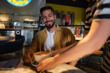 Young man receiving his coffee from a waitress