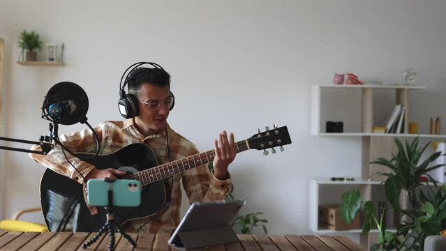 young man with guitar recording with microphone, influencer recording live for his audience. tutorial, teacher, online classes