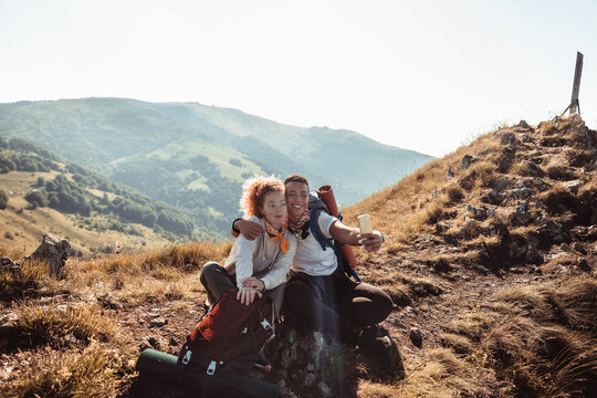 Young mixed lesbian couple taking a selfie while out hiking in the mountains and hills - Powered by Adobe