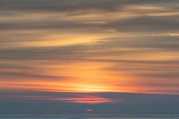 Naklejka na ściany i meble Winter sunrise over the sea in a cloudy sky.