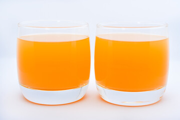 Glass glasses with orange juice on a white background. Delicious orange cooling drink.
