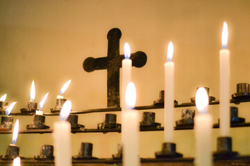 Velas en iglesia y una cruz en el fondo 