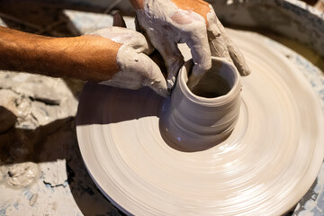 Closeup of the male hands doing pottery using clay on a potter's wheel.