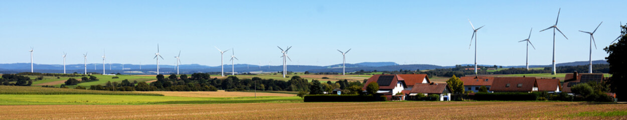 a small village in front of a wind turbine park panorama