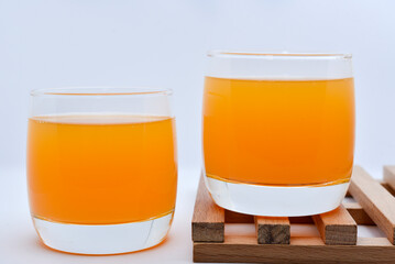 Glass glasses with orange juice on a wooden stand. A soft drink in a glass on a white background.