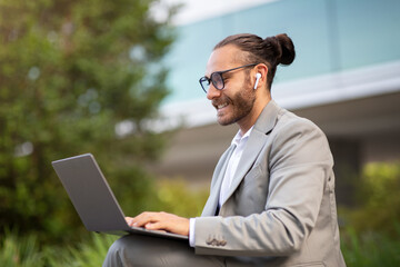 Remote Work. Handsome young businessman using laptop outdoors