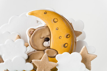 Close up of birthday cake decorated with gingerbread cookies in the shape of Teddy bear sleeping on...