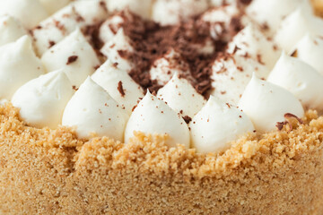 Banoffee cake with banana and caramel sauce filling sprinkled with grated dark chocolate as a textured background. Close up of English traditional pie