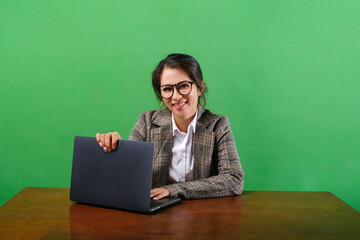 Successful happy Asian business woman sit work at office isolated on green background