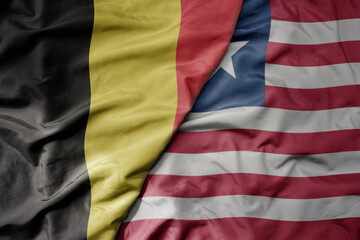 big waving national colorful flag of belgium and national flag of liberia .