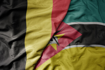 big waving national colorful flag of belgium and national flag of mozambique .
