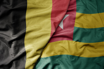 big waving national colorful flag of belgium and national flag of togo .