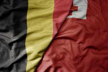 big waving national colorful flag of belgium and national flag of Tonga .
