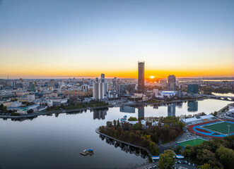 Fototapeta premium Yekaterinburg city and pond aerial panoramic view at summer or early autumn sunset. Night city in the early autumn or summer.