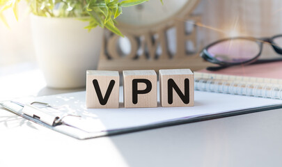 The word VPN is written on wooden cubes between a pen and a calculator on a light background.