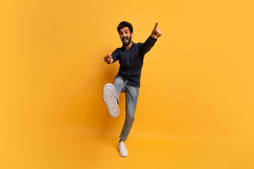 Cheerful young indian man pointing at camera and showing shoe sole