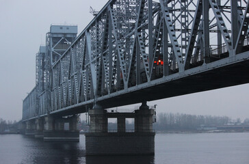 The train is traveling over a bridge over a river in thick fog. Gray background, color photo. Mystical picture