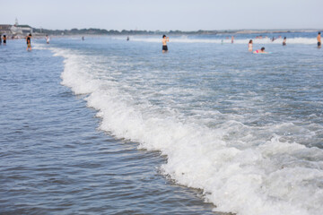 beach scene captures the essence of a scorching summer day, where people revel in the refreshing waters, laughter, and endless fun under the blazing sun