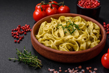 Delicious fresh pasta with pesto sauce, salt, spices and herbs on a ceramic plate