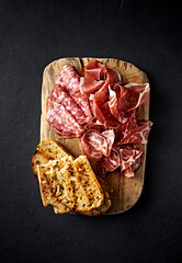 Italian Parma Ham, Coppa and Salami with bread toasts on wooden chopping board. Traditional antipasto. Top view - 644612642