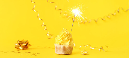Tasty birthday cupcake with sparkler on yellow background