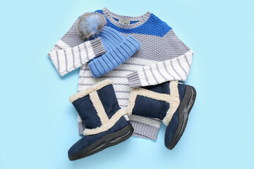 Stylish children's sweater, shoes and warm hat on color background