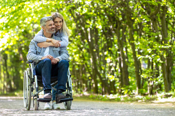 Loving couple disabled husband in wheelchair and wife in park.