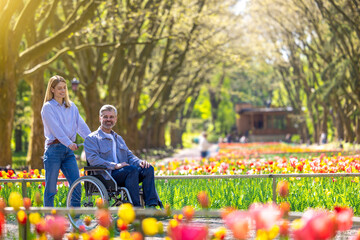 Loving couple disabled husband in wheelchair and wife in park.